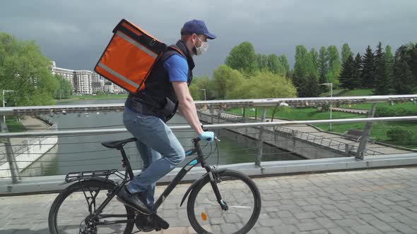 Food Delivery in the Conditions of a Viral Pandemic, Courier in Medical Mask with a Thermo Backpack