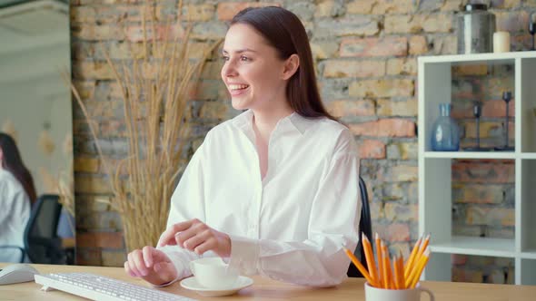 Young Peaceful Businesswoman Having a Cup of Tea at Her Working Place