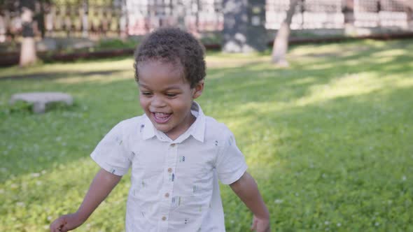 A Cute African Boy Runs in the Park and Laughs