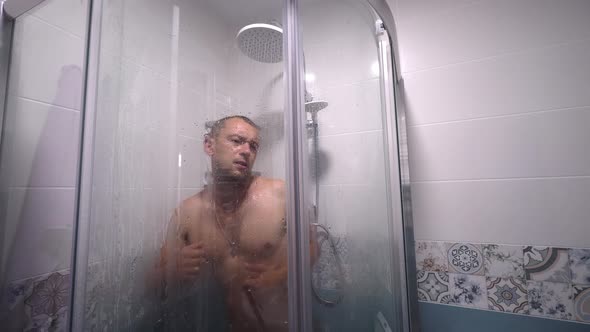 Man taking shower washes his hair underwater in shower in shower.