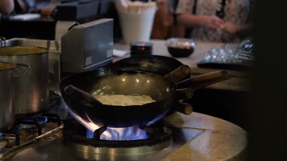 Chinesse Chief Cook Cooking on the Wok Pan with Flambe on the Asian Restaurant Kitchen Pasta Seafood