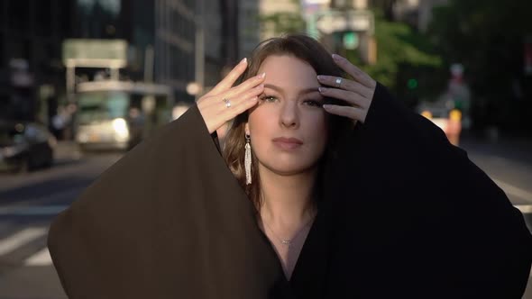 Young Brunette Woman in Black Dress with Sleeves Posing at Streets of New York