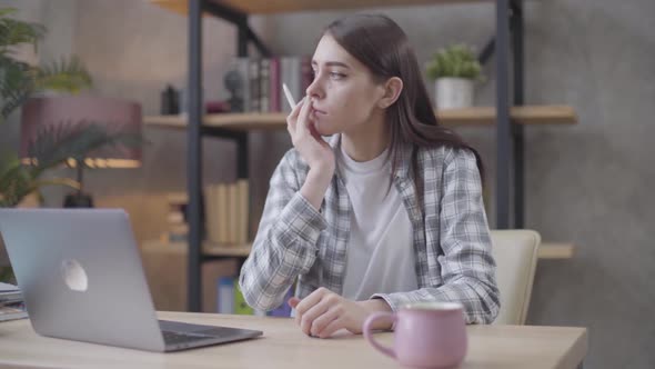 Nervous Caucasian Businesswoman Sitting at the Table with Laptop and Thinking. Irritated Female