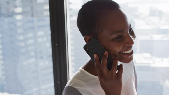 Portrait of smiling african american businesswoman having call at window