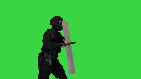Riot Police Officer Hitting His Riot Shield While Moving Forward with the Shield Up on a Green