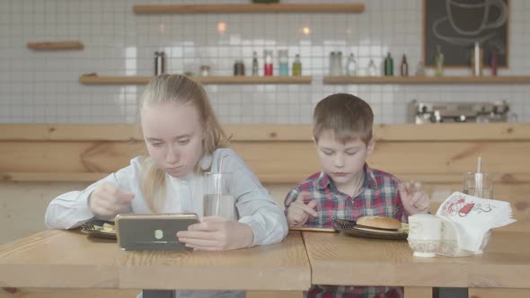 Kids with Phones Enjoying Fast Food Meal in Cafe