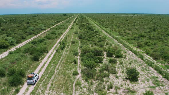 Driving On Dirt Road With Fence Line Among Vegetations In Central Kalahari Game Reserve, Botswana. A