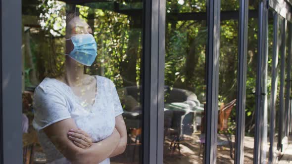 Asian woman wearing face mask and looking through window