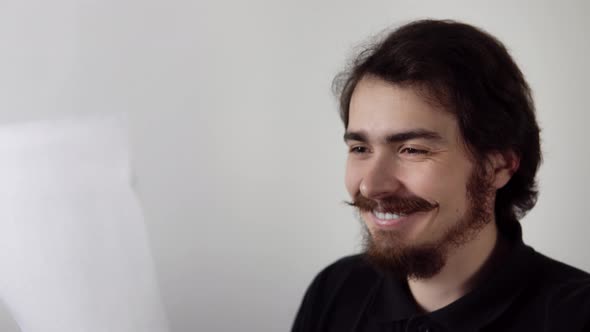 Man Reads Information on Sheet of Paper in His Hand and Becomes Happy Smiling Then Hugging Letter