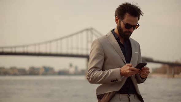 Businessman In Suit Chatting On Mobile Phone With Friend  Sending Message On Social Network.