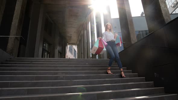 Smiling Girl Walking From Centre Mall with Shopping Bags, Happy with Purchase on Black Friday