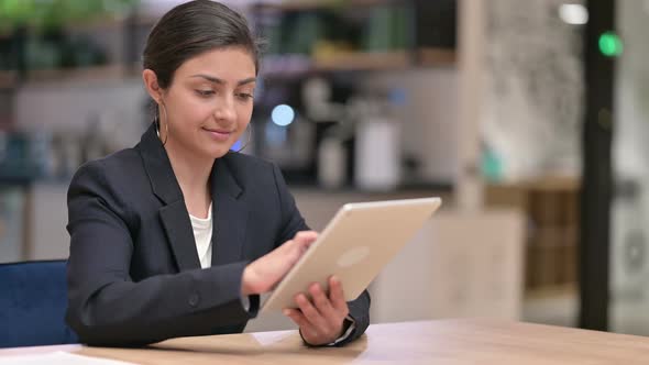 Serious Professional Young Indian Businesswoman Using Tablet in Cafe