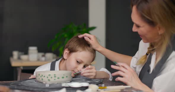 Mother Potter Helping His Son Making Pattern on the Bowl in Pottery Studio