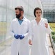 Two Researchers in Laboratory Robes Walk Around the Greenhouse. They Discuss the Success of Doing - VideoHive Item for Sale