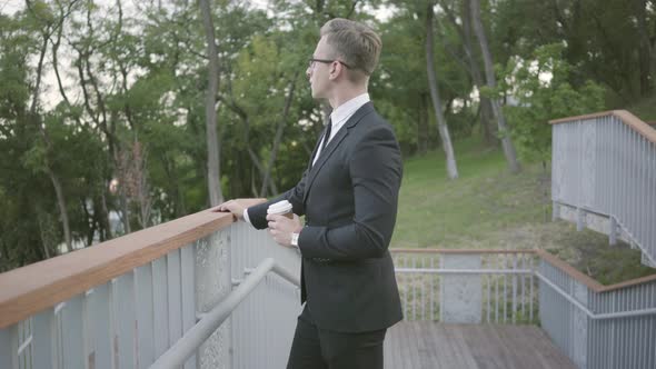 Young Successful Businessman Standing on the Terrace with Coffee