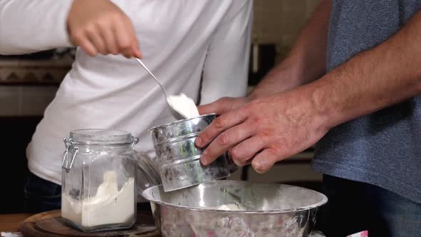 Children helping parents to preparing a dough in domestic kitchen