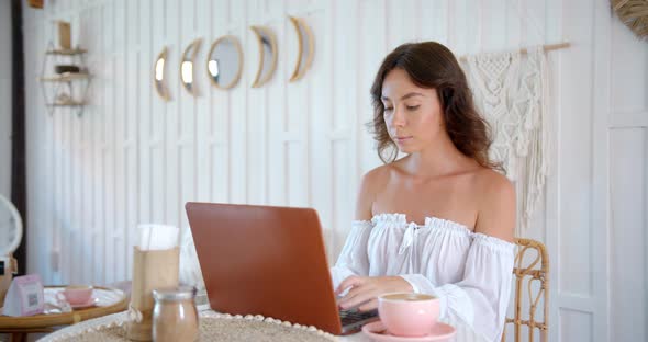 Young Woman Works at White Cozy Cafe She Drinks Coffee and Typing on Her Lap Top Computer