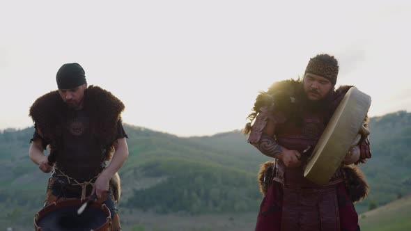 Folk Musicians in Ethnic Clothes Play Drums in Valley