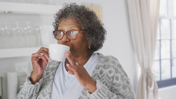 Senior mixed race woman enjoying drinking tea. Social distancing and self isolation in quarantine