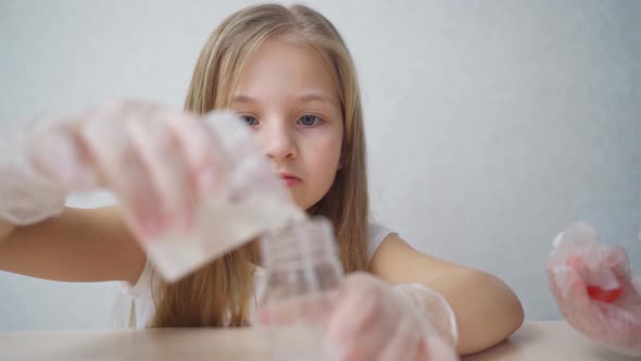 a Cute Little Girl in Protective Gloves Conduct an Experiments at Home