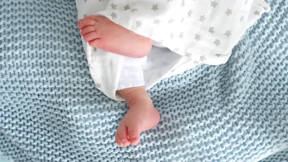 feet of a newborn baby from under the covers
