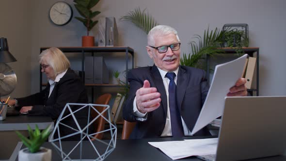 Mature Elderly Man Accountant Reading Documents Analyzing Financial Papers Raising Hands in Surprise