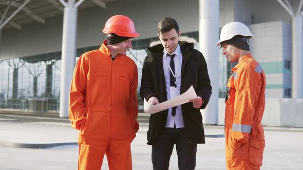 Investor of the Project in a Black Suit Examining the Building Object with Construction Workers in