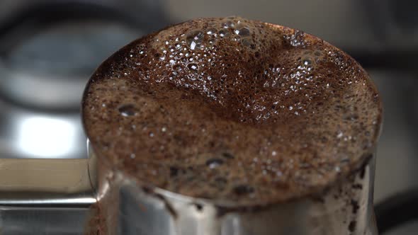 Black raw coffee boiling in turk. Preparation of turkish coffee in cezve