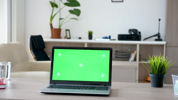 Laptop with Green Screen on a Desk in the Living Room