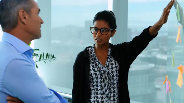 Executives reading sticky notes on glass board