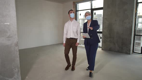 Masked Realtor and Buyer Walking Around Apartment