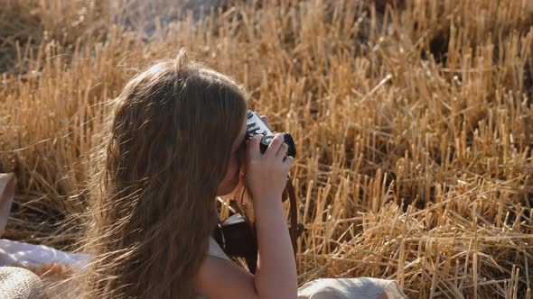 Serious Child Girl with Long Hair Sits on a Mown Wheat Field