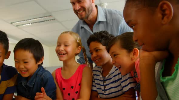 Adult Caucasian male teacher teaching kids on laptop in classroom at school 4k