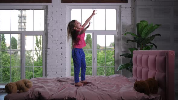 Joyful Cute Little Girl Jumping on Bed in Nursery alt