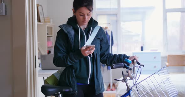 Woman using her mobile phone while taking her bicycle out 4k