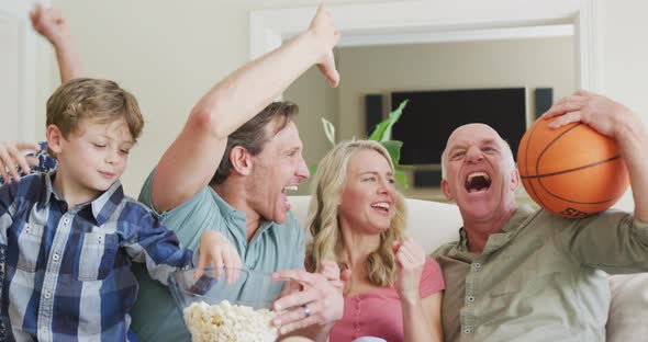 Happy caucasian family watching tv and supporting in living room