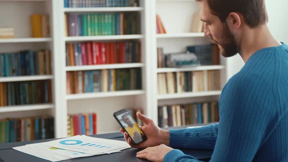 Young male working with smartphone indoors. Working male with laptop screen