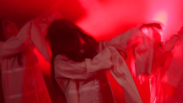 Three Charming Girls in White Shirt Are Dancing on the Stage. Shot in a Dark Studio with Smoke and