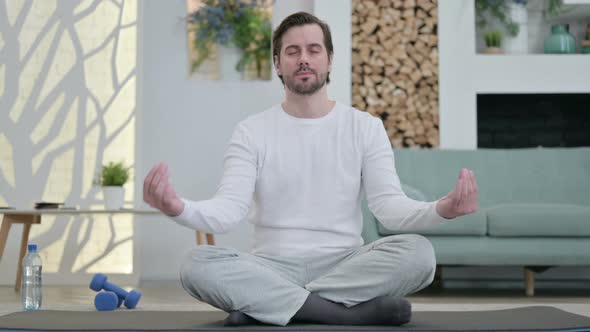 Portrait of Young Man Meditating on Yoga Mat at Home