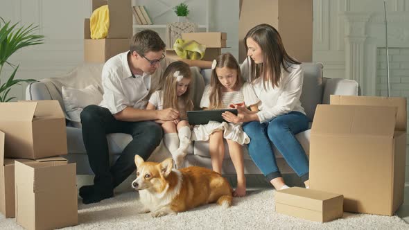 A Happy Family Uses a Tablet for Online Shopping, Sitting on the Couch at Home