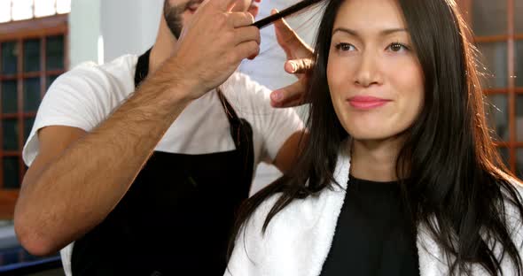 Woman getting his hair trimmed with scissor