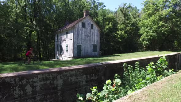 Steadicam following along with a beautiful middle-aged woman biking past an old blockhouse on the C&