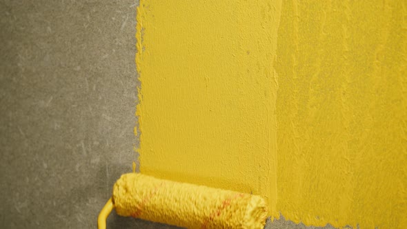 Painting Walls with Yellow Paint Using Roller Closeup