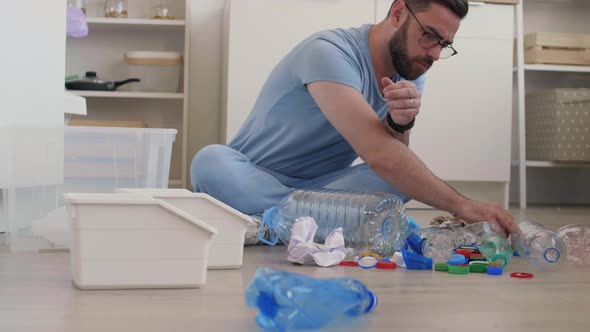 Man Sitting on Kitchen Floor and Sorting Plastic Waste