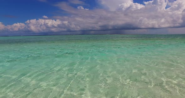 Wide angle flying abstract view of a white sand paradise beach and blue water background in 4K