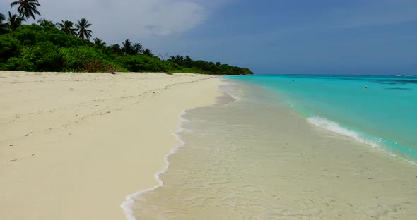 Tropical fly over travel shot of a paradise sunny white sand beach and aqua blue ocean background in