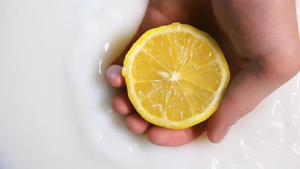 Man's Hand Putting Orange Half Into Milk