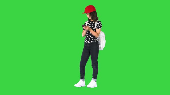 Young Girl Wearing a Backpack and Using Smartphone on a Green Screen Chroma Key