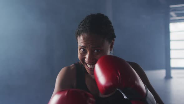 African american woman wearing boxing gloves training throwing punches in empty room