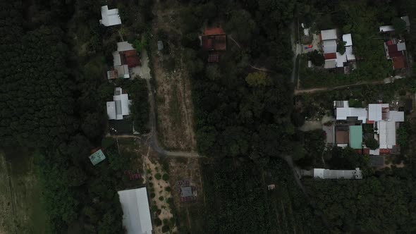 Aerial top down shot of Cu Chi, Vietnam with greenhouse farm houses, forests on sunny day with blue